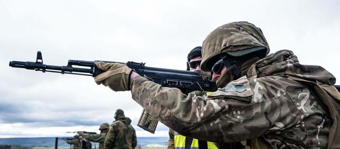 A Ukrainian soldier fires a rifle under the supervision of a Norwegian Army instructor.